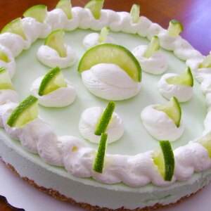 Close up view of a frozen margarita pie garnished with white icing and lime slices on a white platter