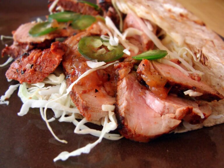 Closeup of grilled pork tacos al pastor with shredded cabbage and fresh jalapeno slices