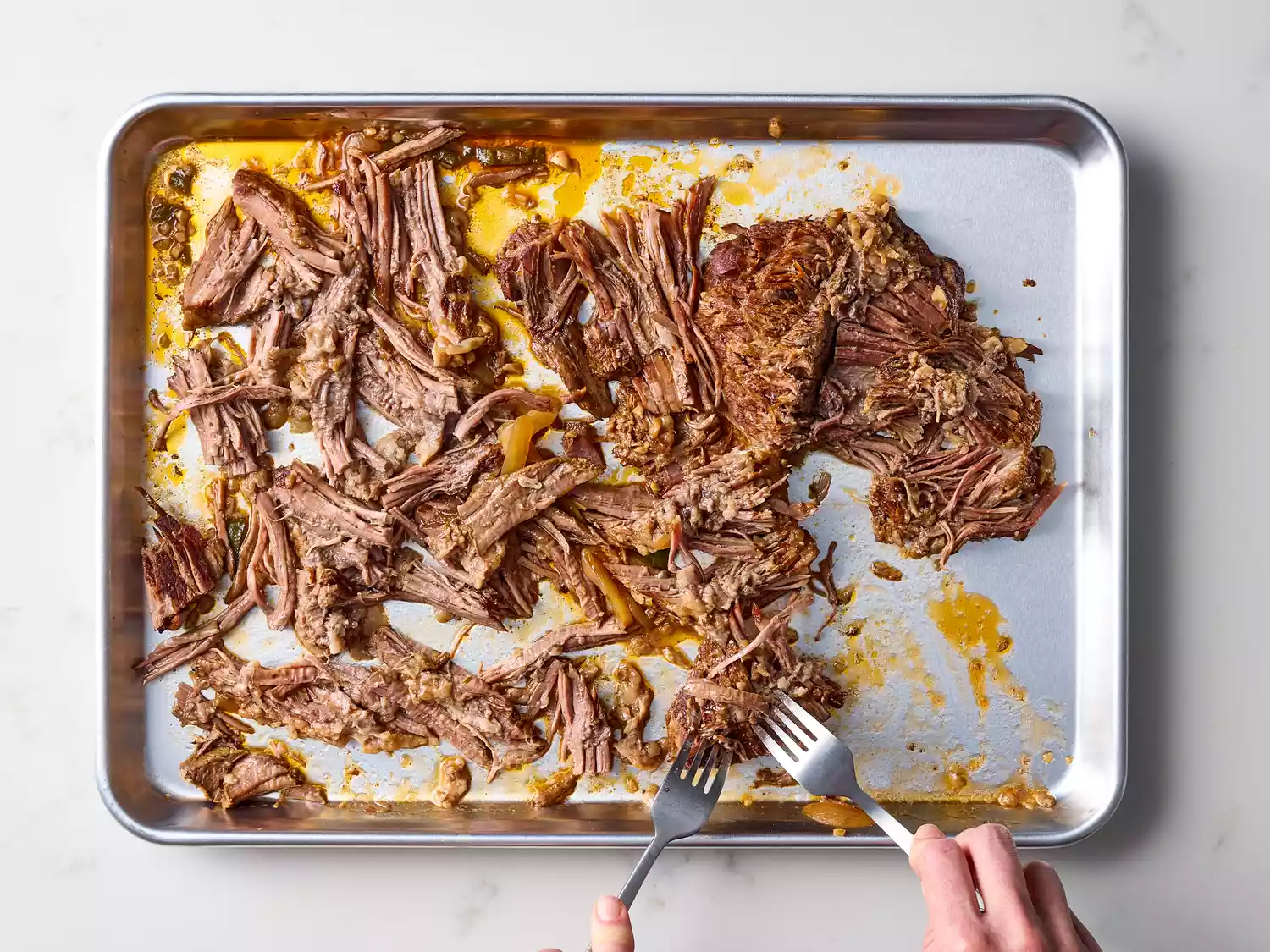 Shredded brisket being pulled apart with two forks