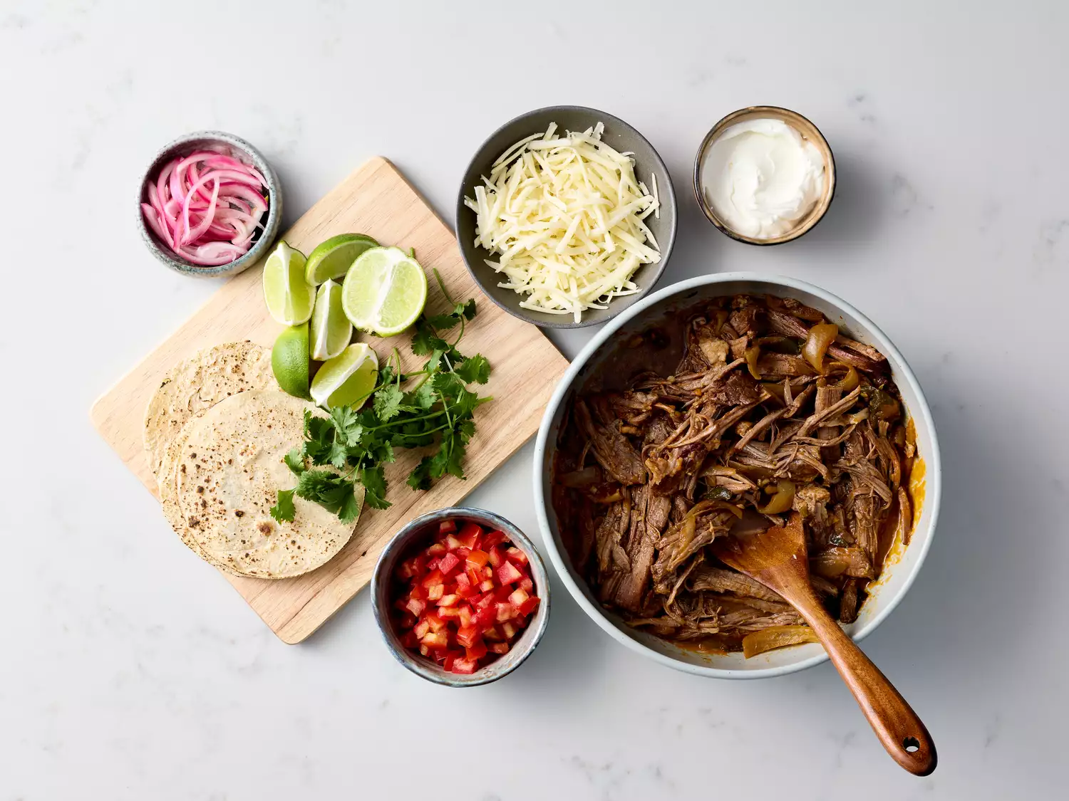 Shredded brisket and taco toppings arranged for serving