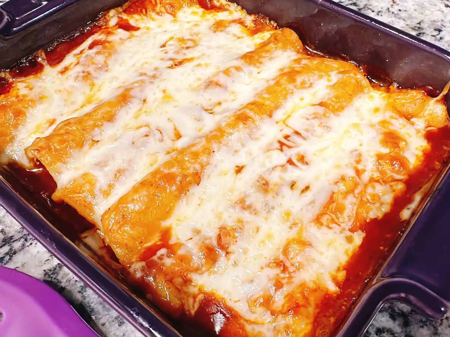 purple baking dish of rotisserie chicken red enchiladas