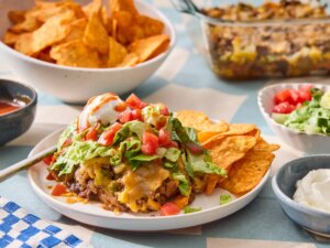 Taco salad casserole served on a plate with tortilla chips and toppings, surrounded by various dishes and condiments