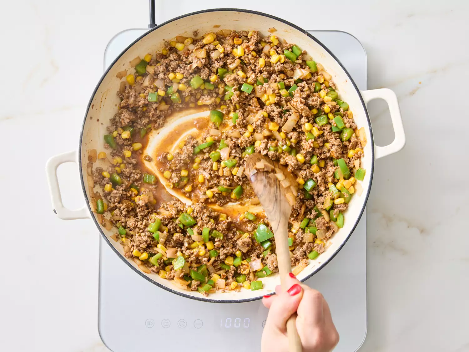 Cooking ground beef mixture with vegetables in a pan on an induction stove