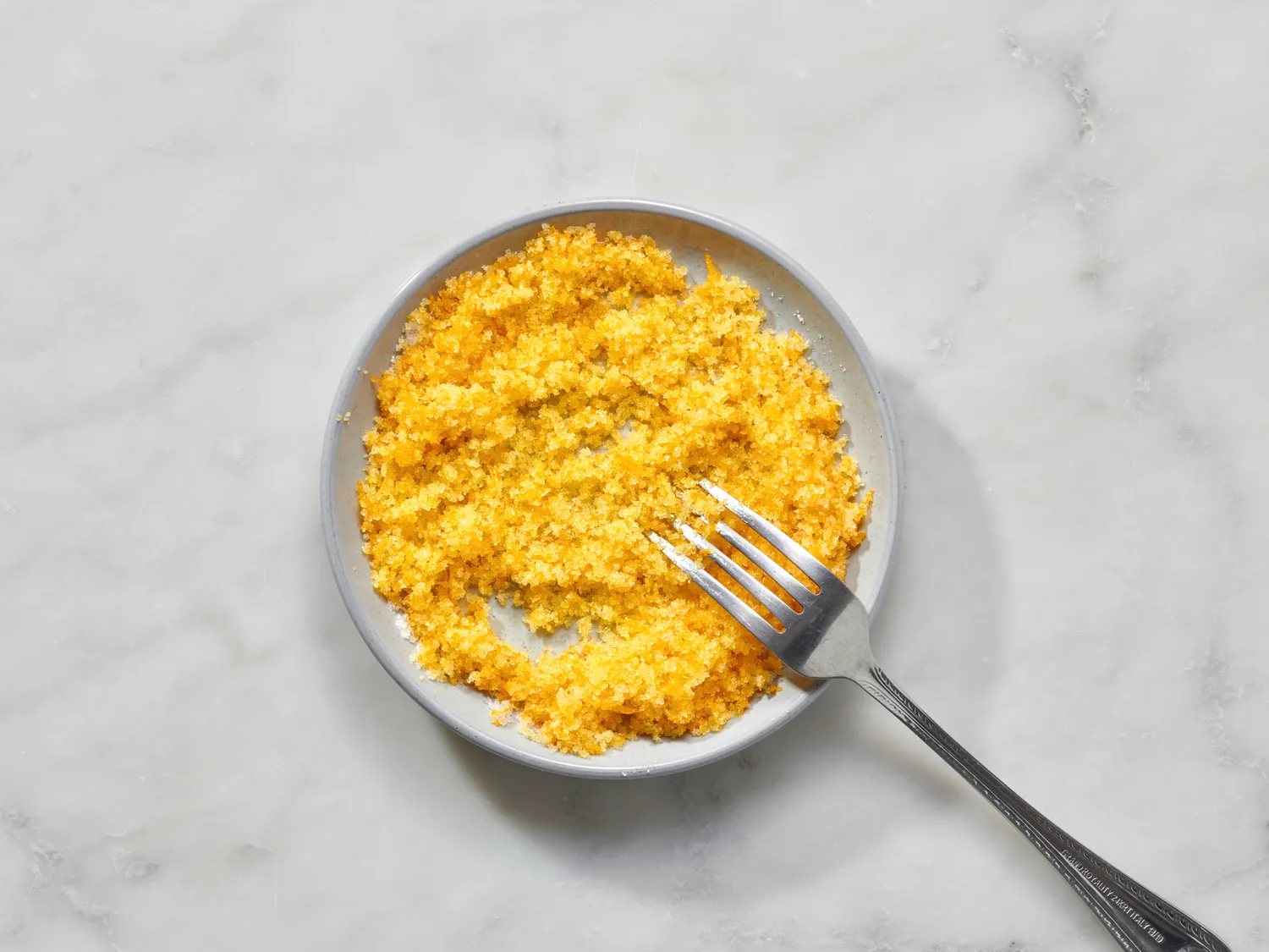 Bowl of orange-flavored sugar with a fork, used in a recipe preparation
