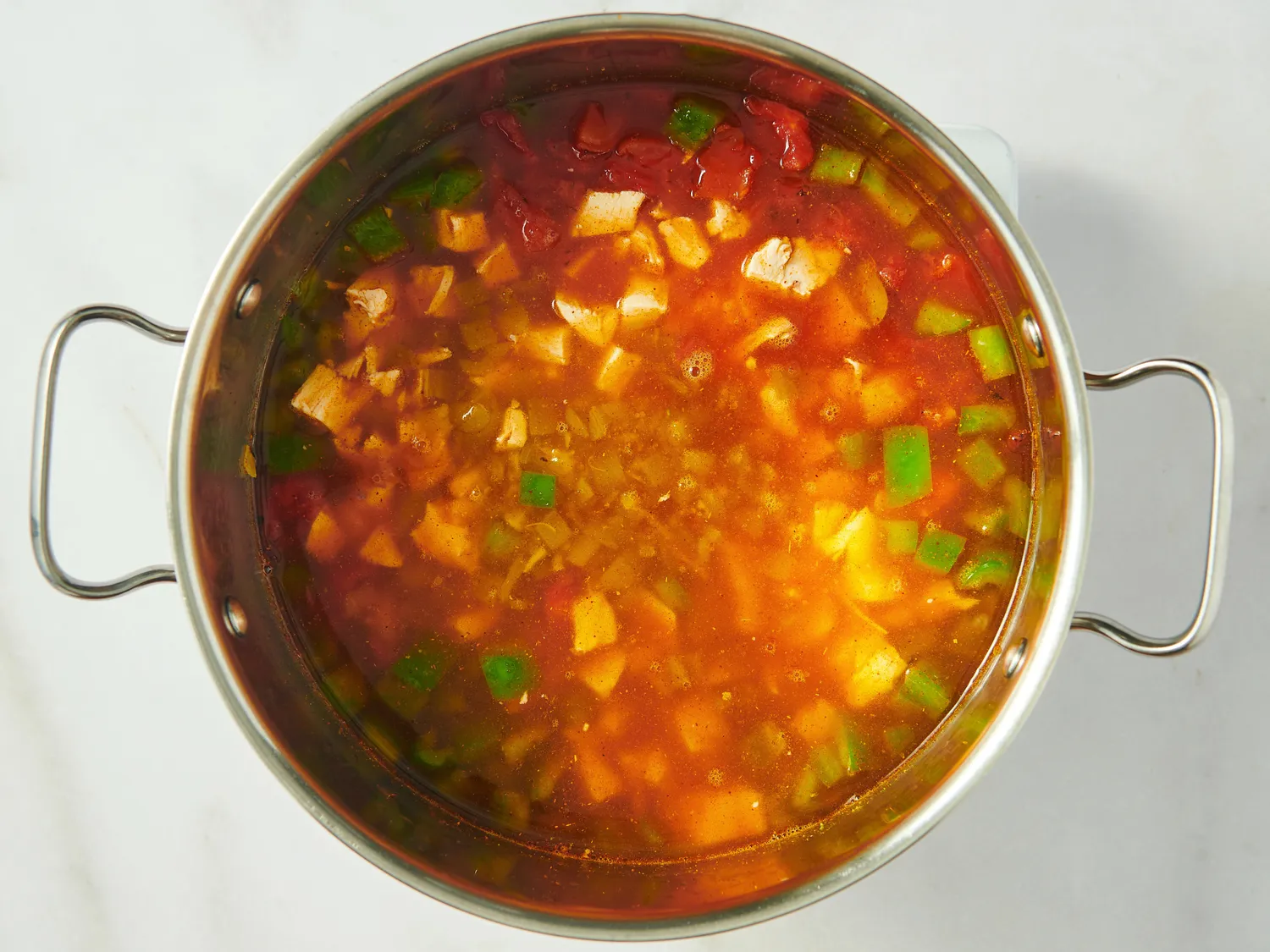 A pot filled with chicken tortilla soup featuring visible vegetables and broth