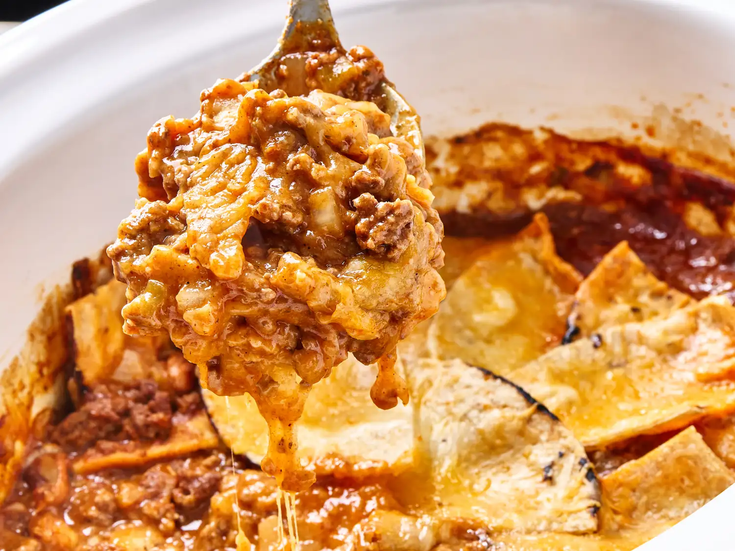 Spoonful of enchiladas being served from a slow cooker