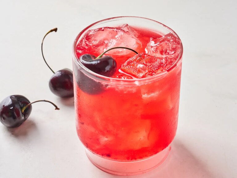 A cherry margarita glass filled with ice and cherries as garnish