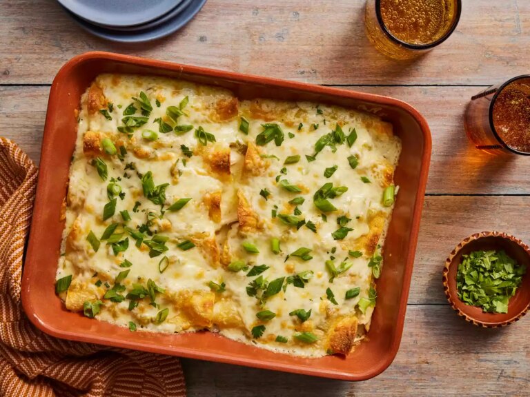 Looking down at a casserole dish of chicken enchiladas, garnished with green onions.