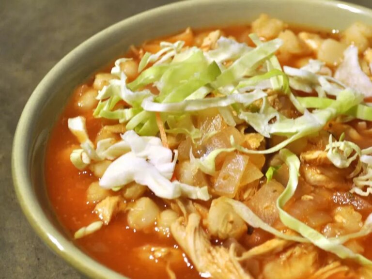 Close up view of traditional pork posole garnished with fresh cabbage in a bowl
