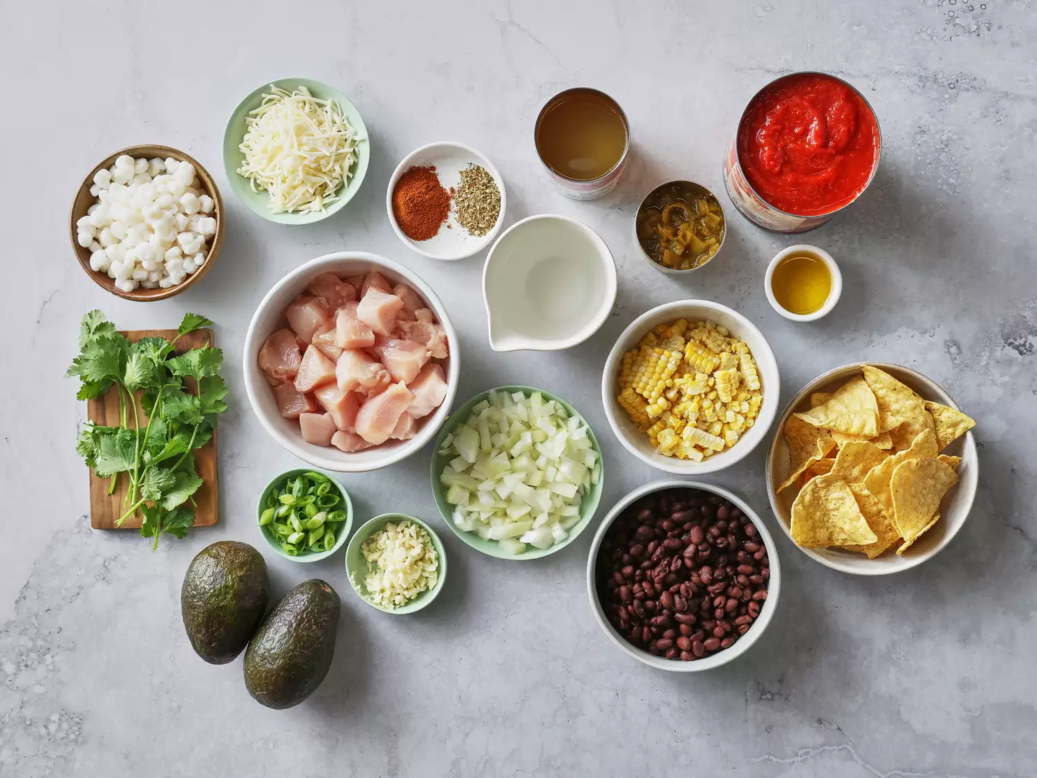 Ingredients for a Mexican-inspired dish, including chicken, beans, corn, and chips.