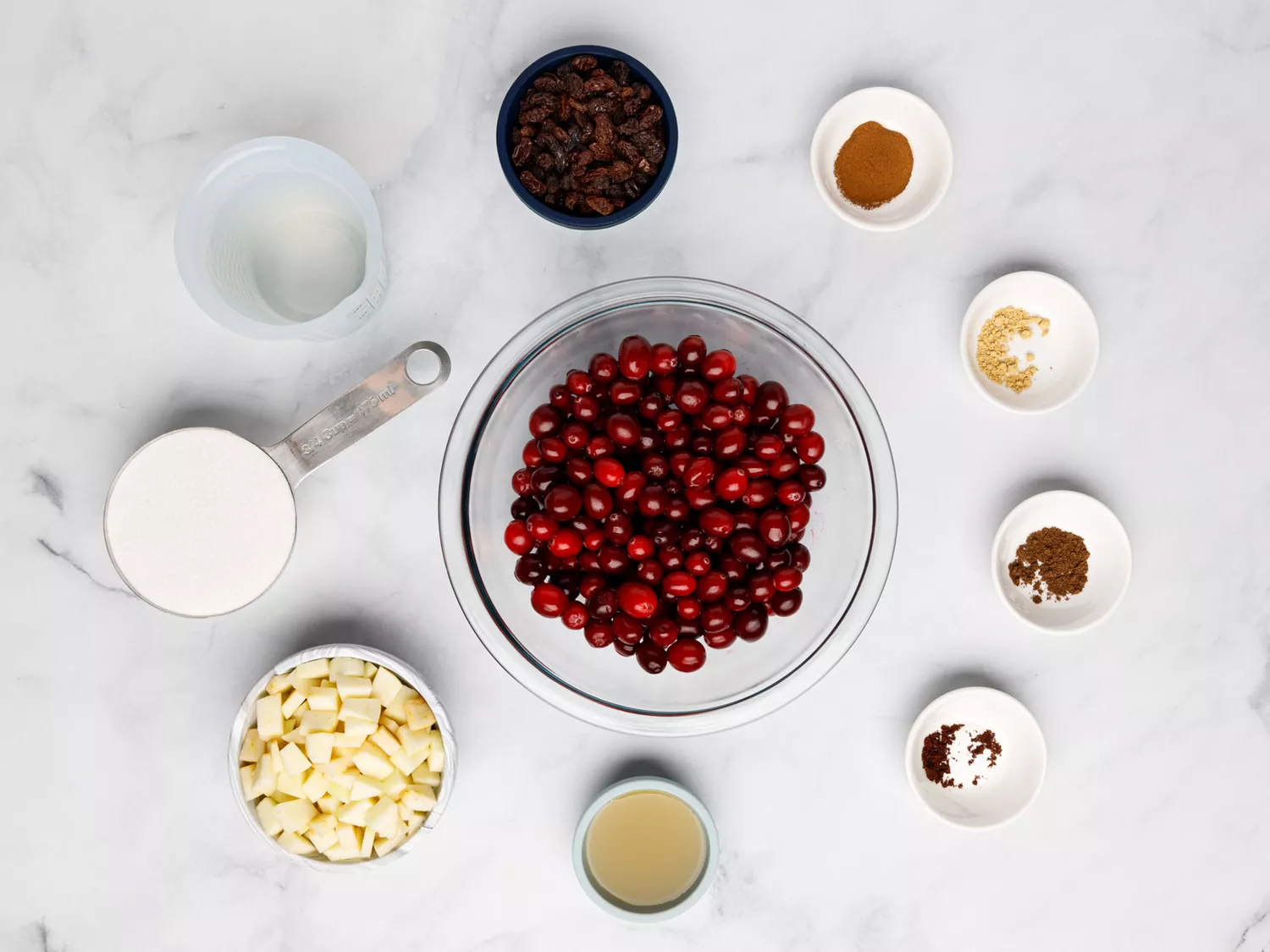 Ingredients for cranberry chutney in separate bowls placed on marble surface