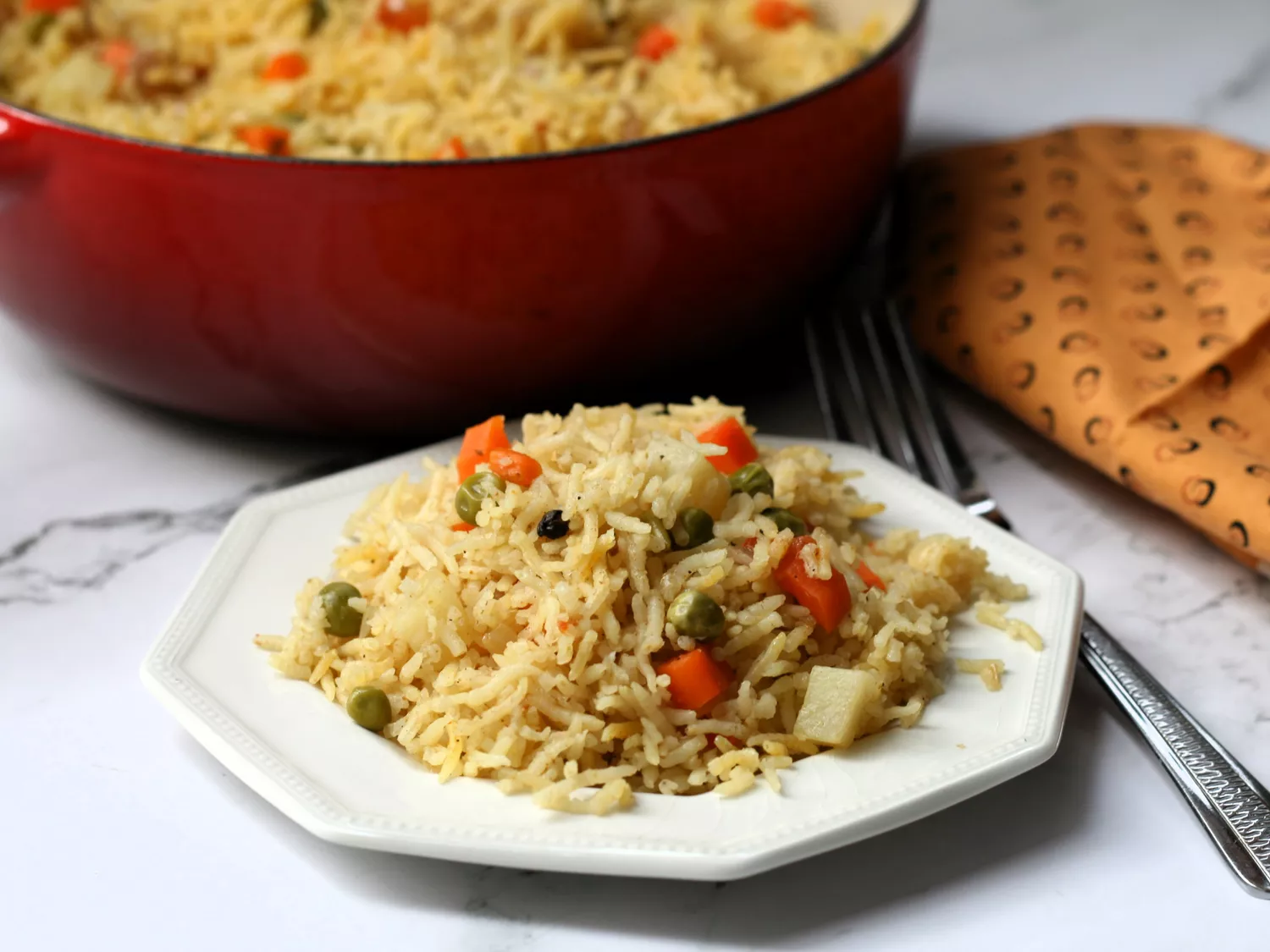Indian vegetable biryani on plate with large pot in background
