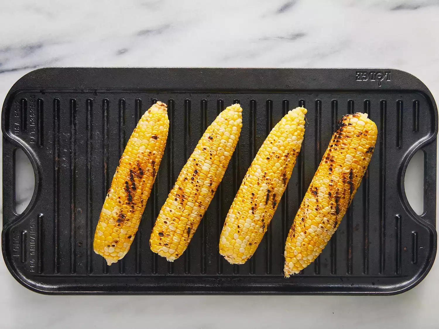 Overhead of corn on the cob being cooked on a grill. 