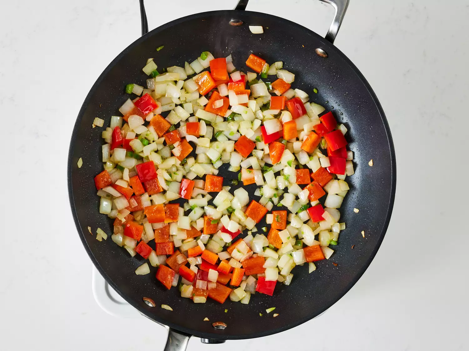 an overhead shot of onion, bell pepper, garlic, and jalapeÃ±o in a pan