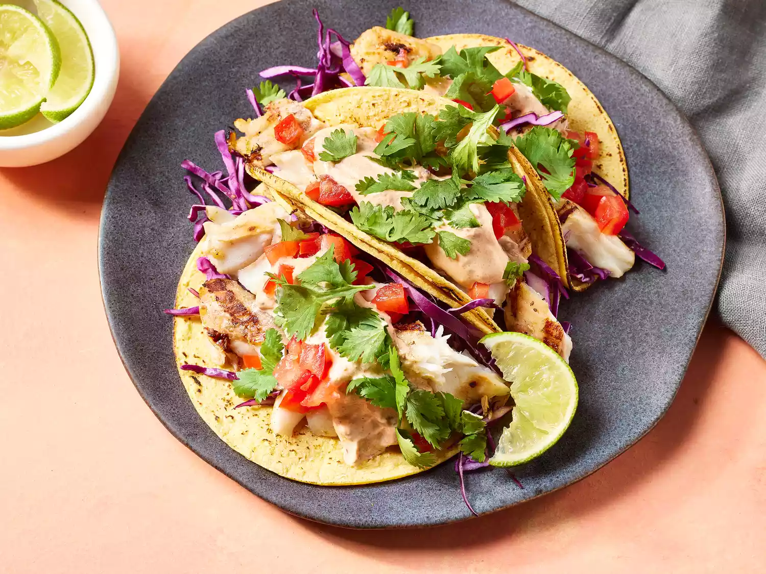 Grilled fish tacos with chipotle lime dressing garnished with cilantro and a lime wedge on a plate
