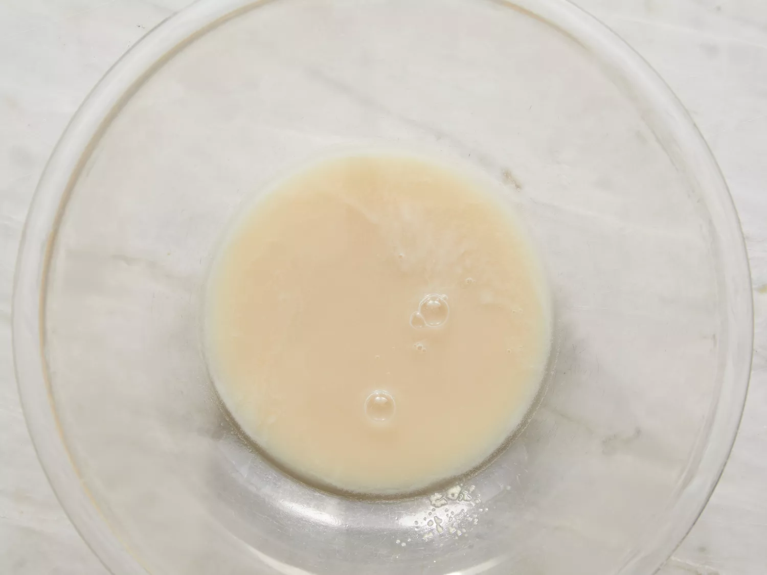 Overhead shot of yeast dissolved in water in a bowl