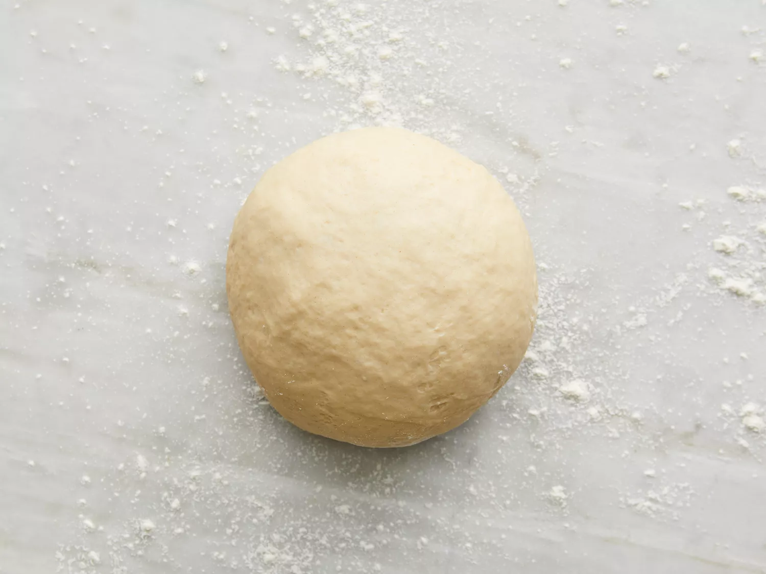Overhead shot of naan dough ball on a floured surface