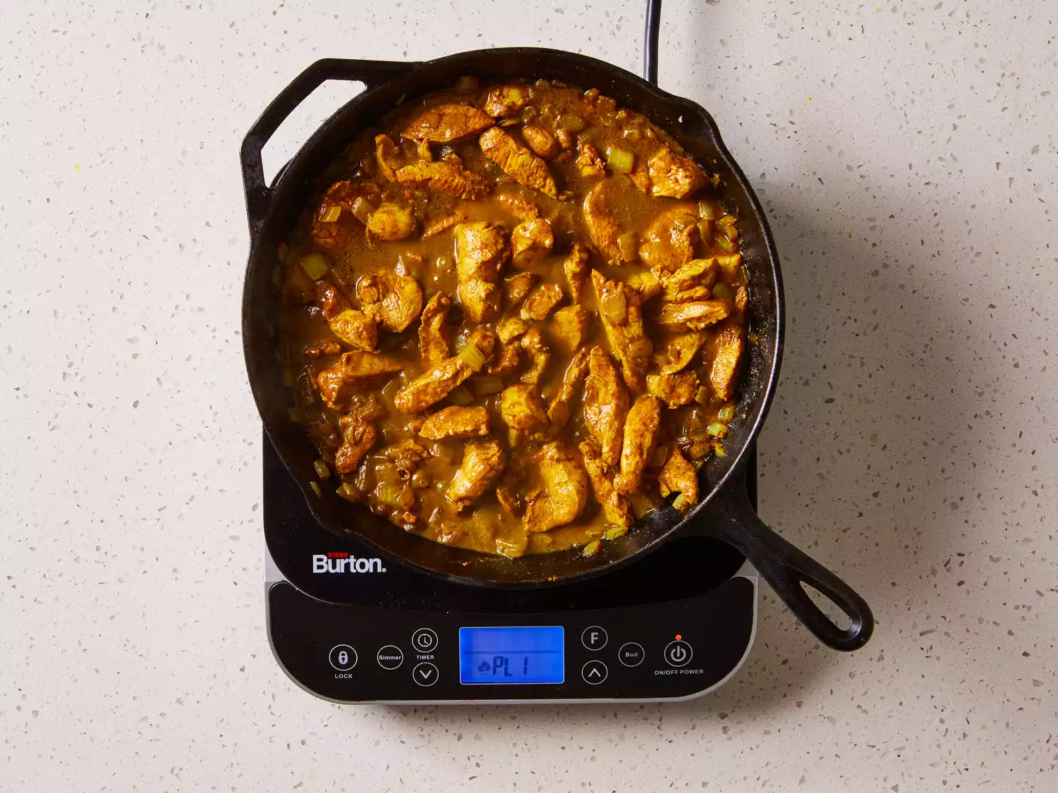Easy Chicken Curry cooking in a cast iron skillet on a burner 