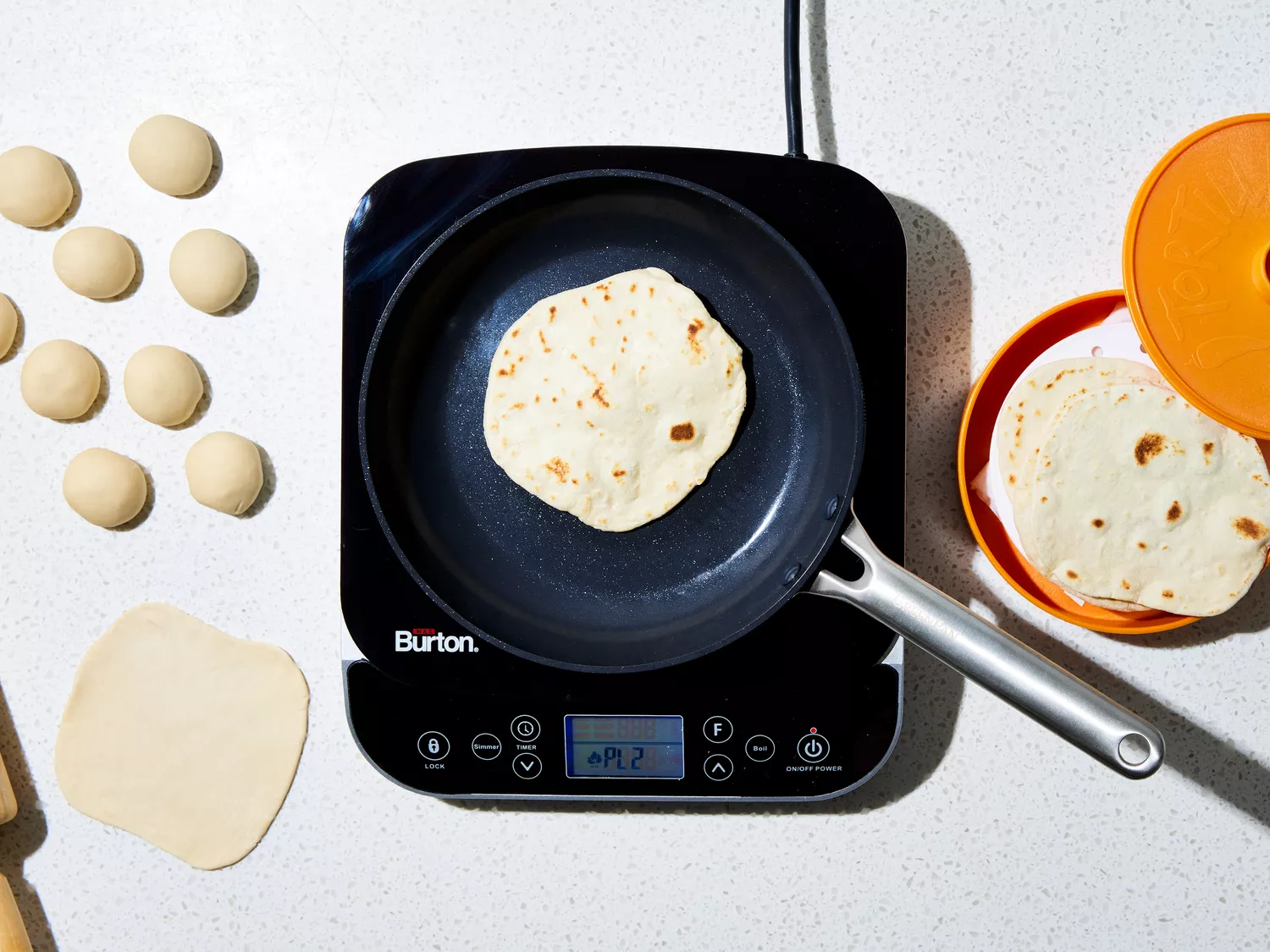 tortillas cooking in a skillet and transferred to a warmer