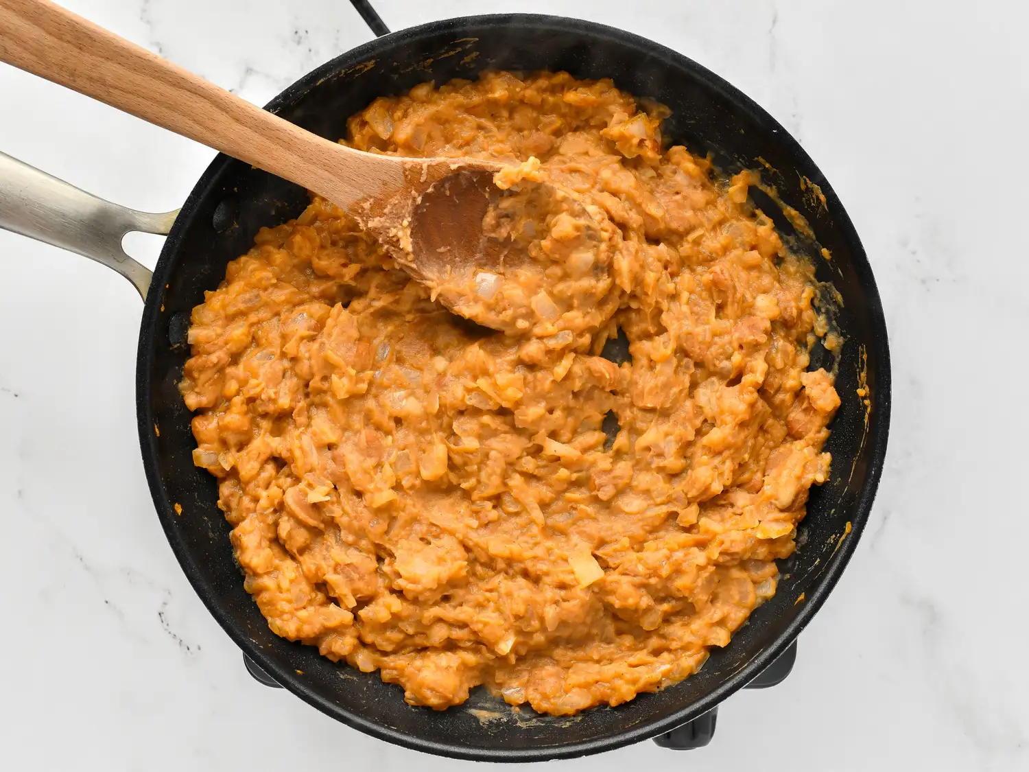 Cooking a creamy casserole mixture in a skillet stirred with a wooden spoon