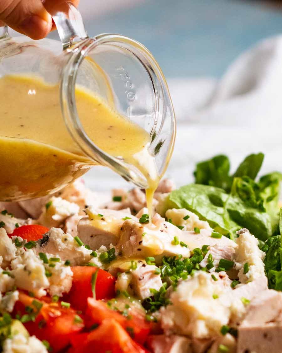 The mighty Cobb Salad Recipe Pouring dressing over Cobb Salad