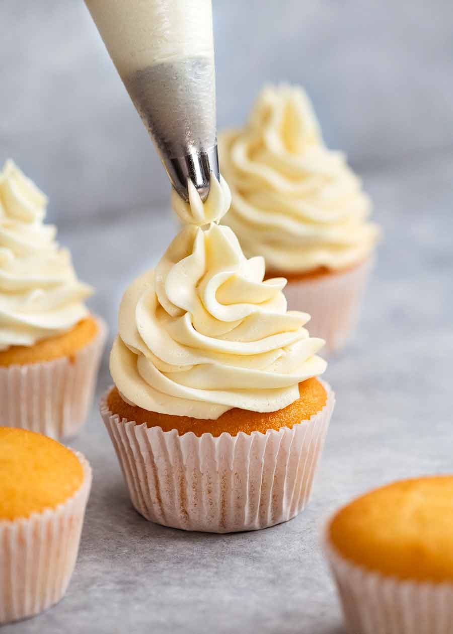 Vanilla Cupcakes (that actually stay moist) Recipe Piping Fluffy Vanilla Frosting onto Vanilla Cupcakes