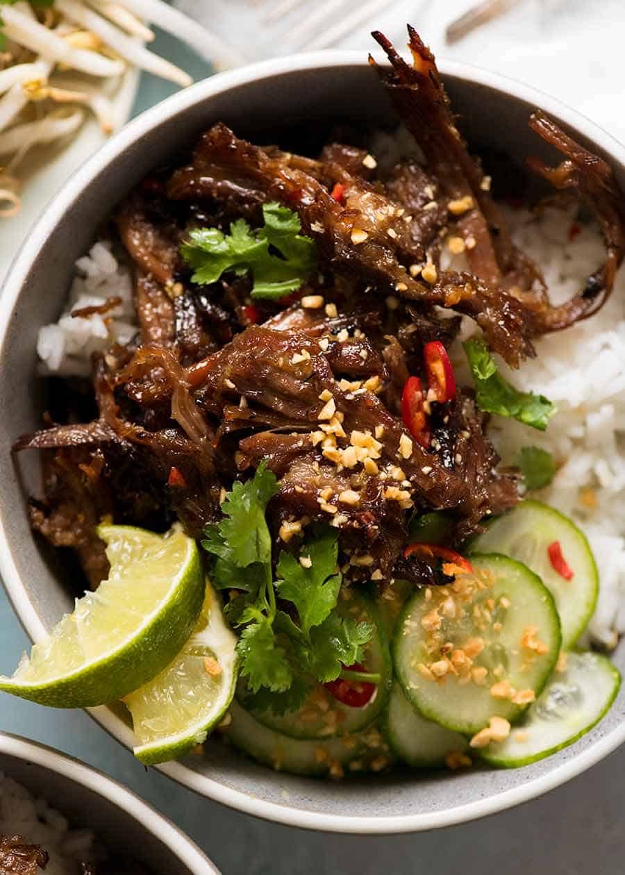Caramelised Vietnamese Shredded Beef Recipe Overhead photo of Caramelised Vietnamese Shredded Beef served over rice with lime wedges, cucumber, chilli and peanuts