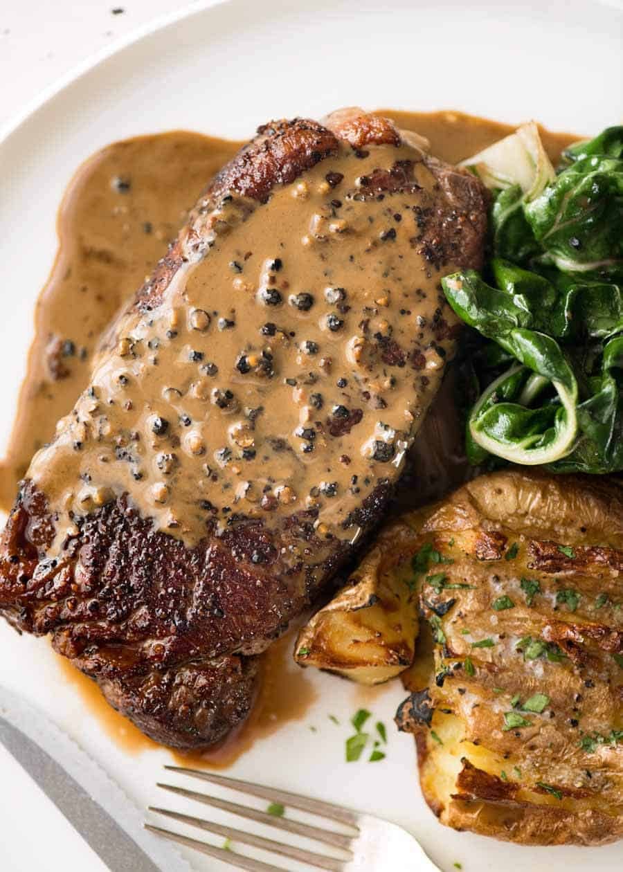 Steak with Creamy Peppercorn Sauce Recipe Overhead photo of Creamy Peppercorn Sauce on steak.