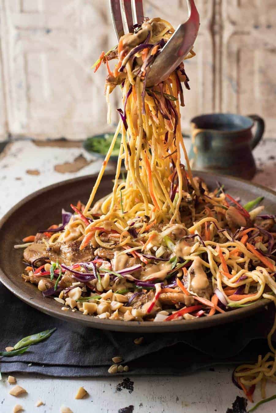 Satay Chicken Noodle Salad being tossed with dressing.