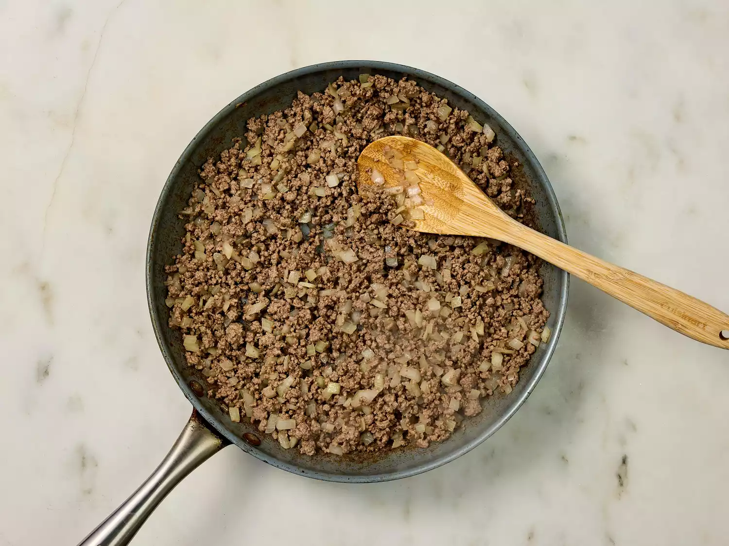Cooked ground beef and onions in a frying pan.