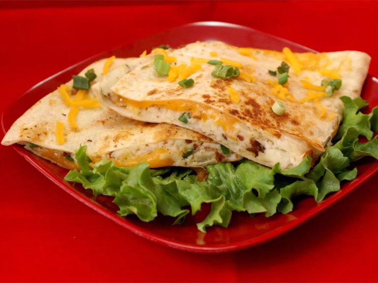 Close up view of sliced mashed potato quesadilla and lettuce on a red plate