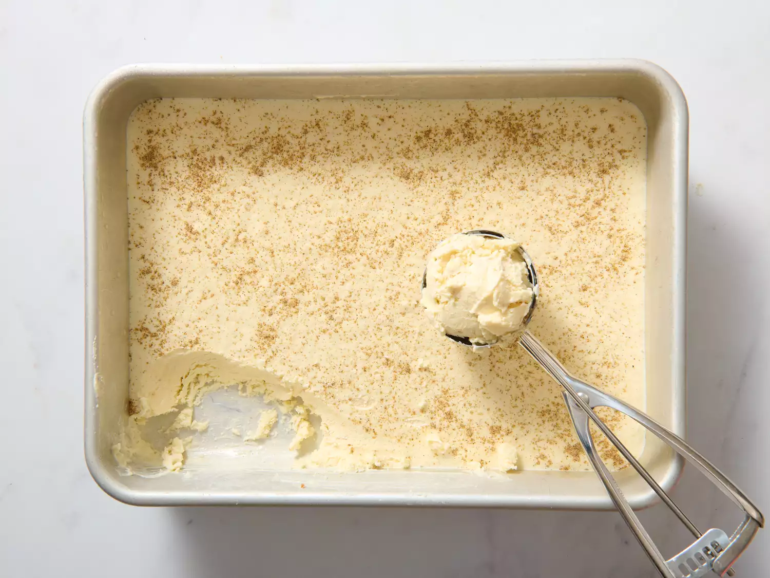 Rectangular tray of kulfi with ice cream scoop forming a mound