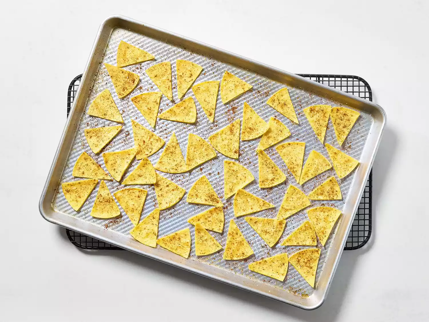 Partially baked tortilla chips on a rack for cooling.