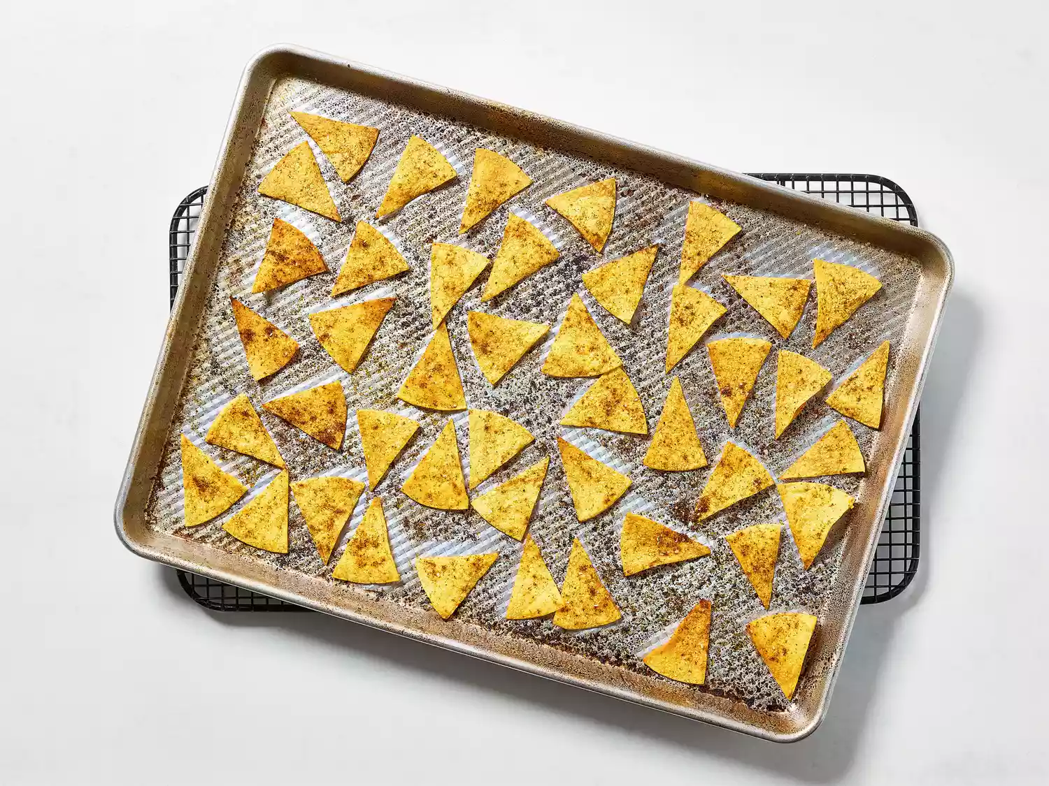 Fully baked tortilla chips cooling on a baking rack.