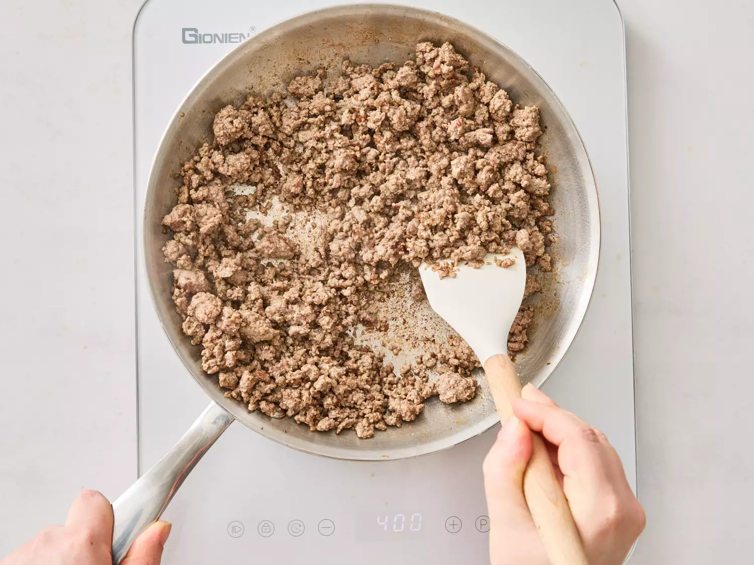 Ground beef being cooked in a skillet on a burner 