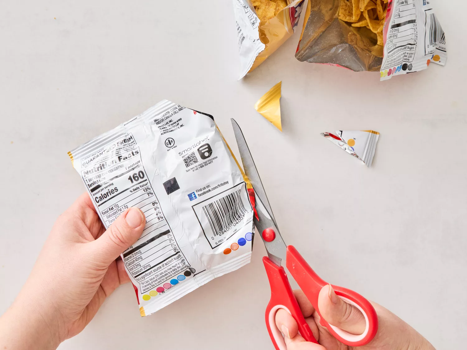 Hand cutting open snack bag with red scissors for taco assembly