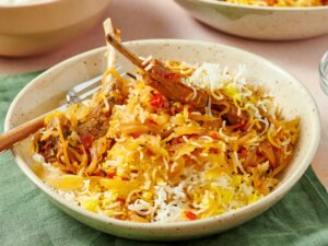A bowl of lamb gosht biryani served on a table with a green napkin