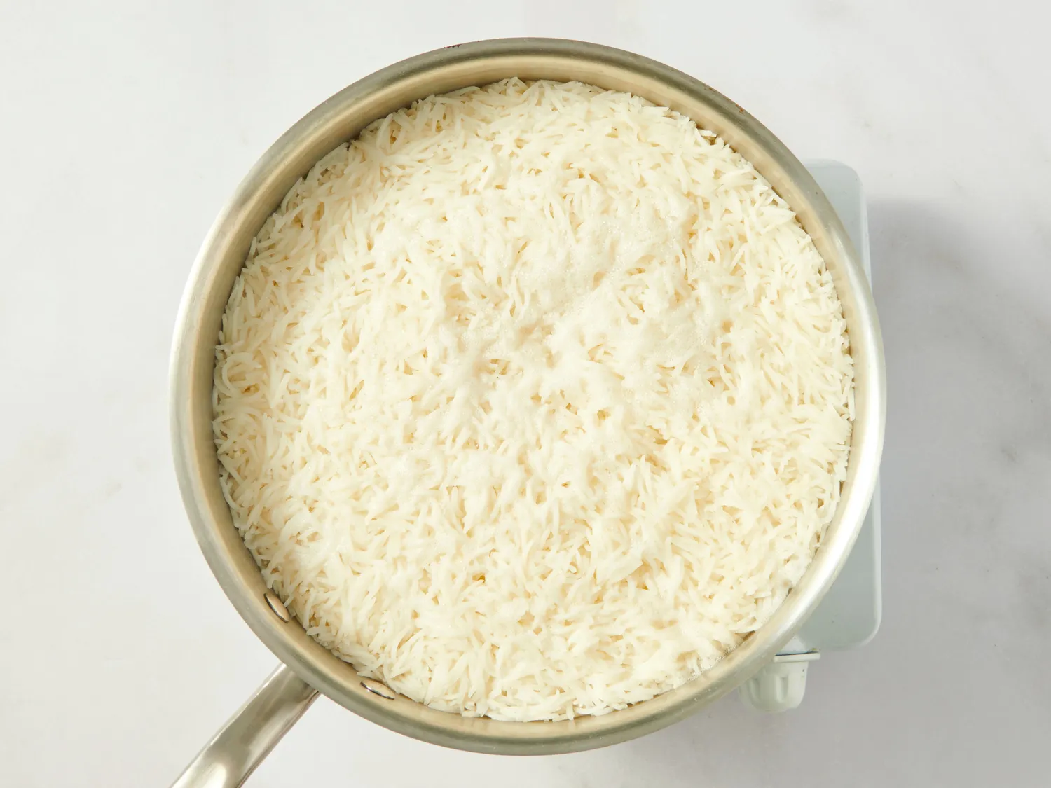 A pot of cooked basmati rice on a white background part of a recipe preparation step