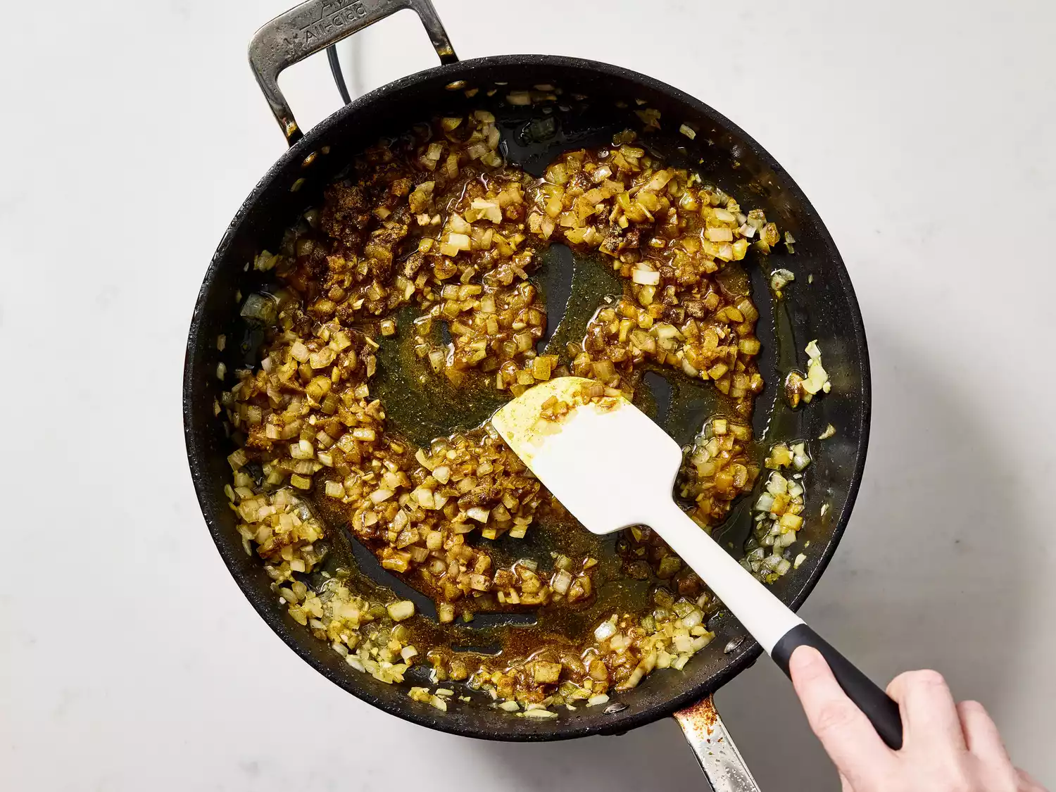 Onions and spices sautéing in oil in a pan.