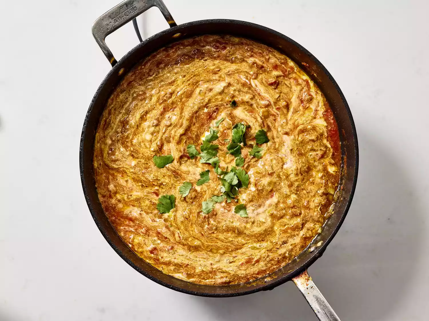 Simmering curry sauce with yogurt and spices in a pan.