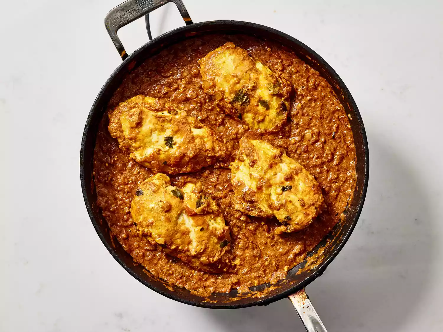 Chicken simmering in a thick, rich curry sauce.