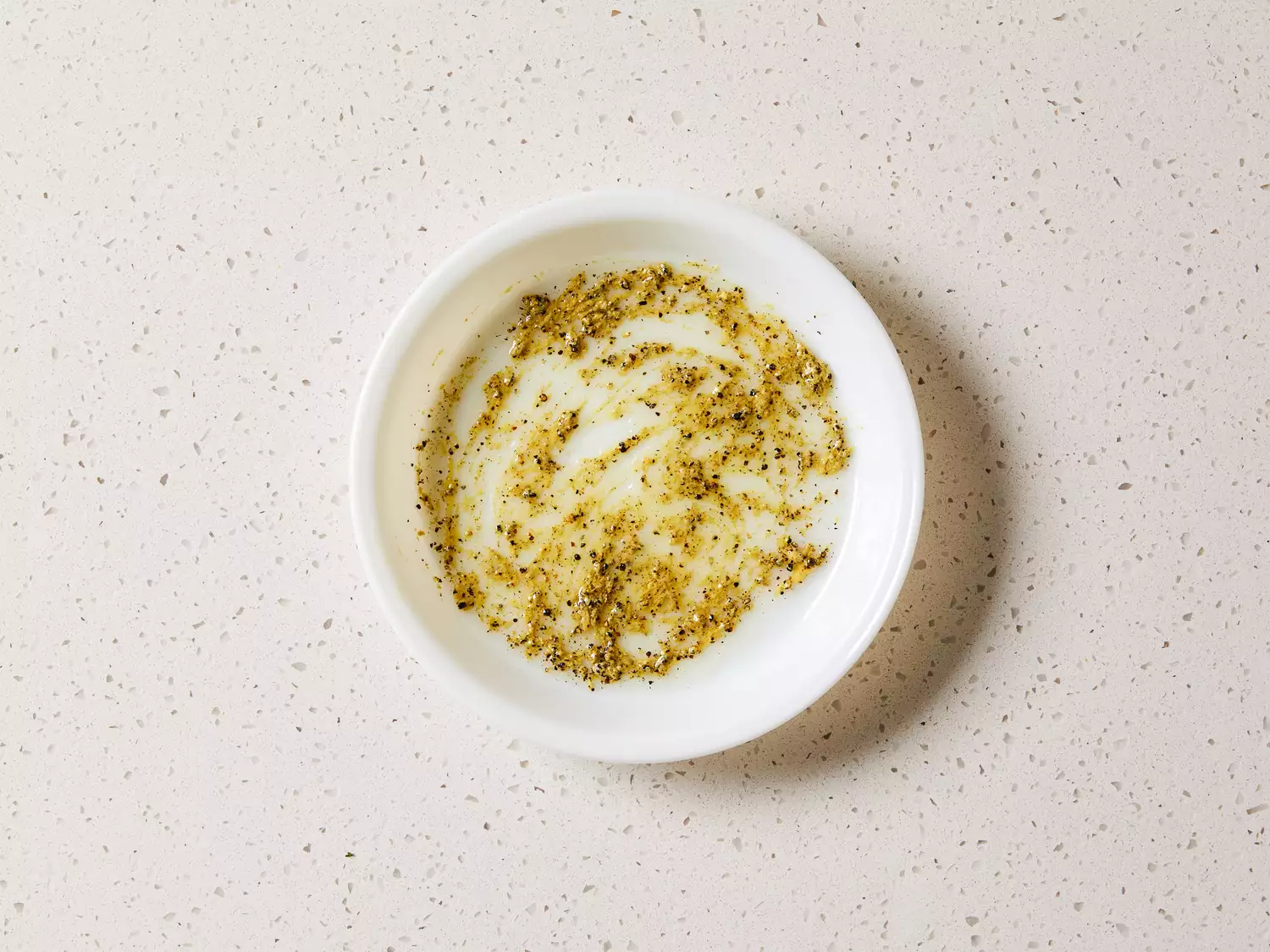 Oil, mustard, black pepper, and salt in a white bowl 