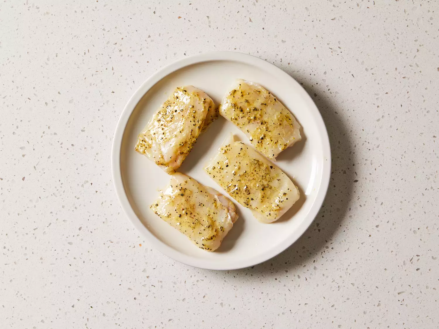 Fish fillets coated with marinade on a platter 