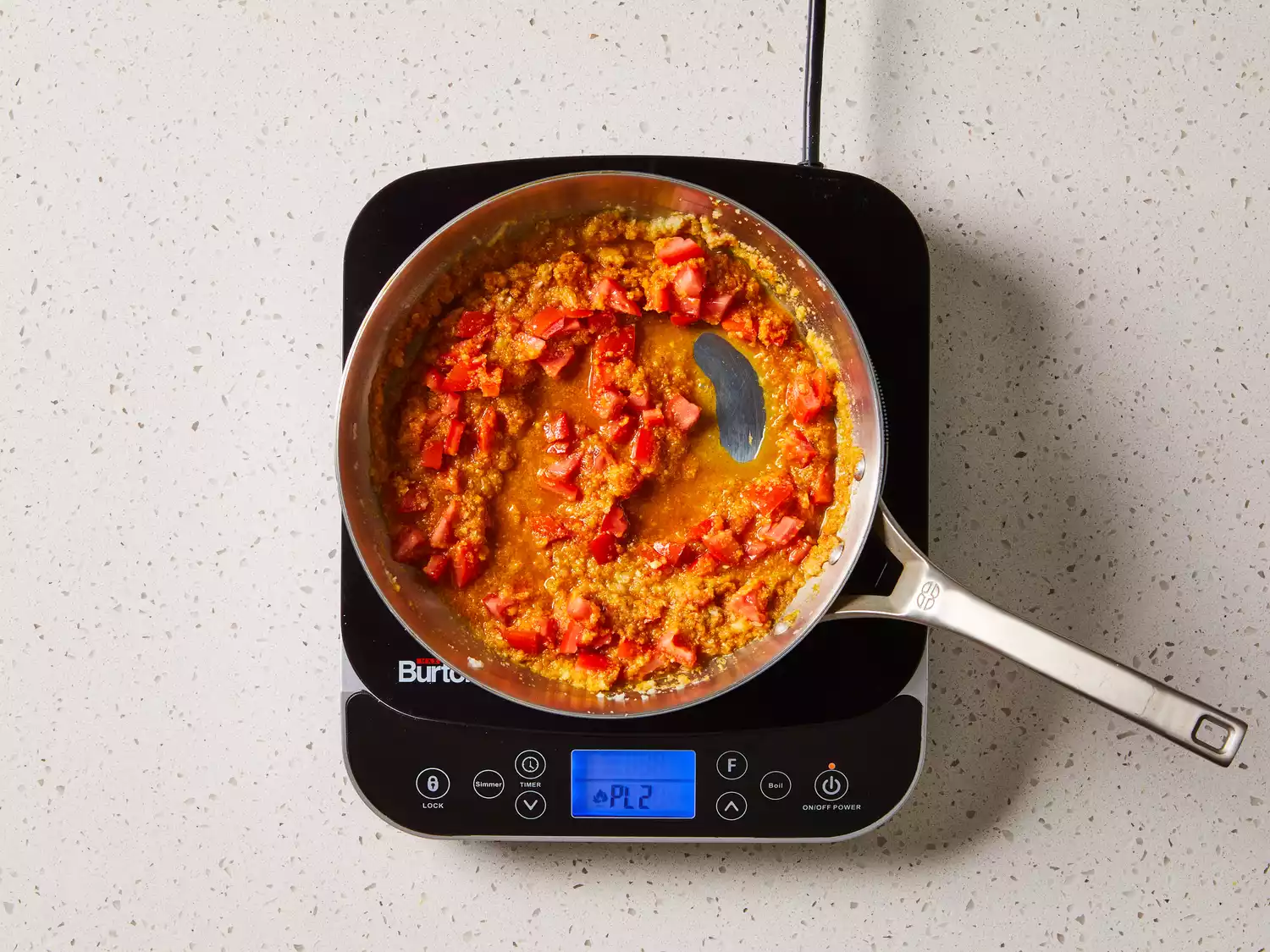 Chopped tomatoes with broth and herbs in a pan on a burner 