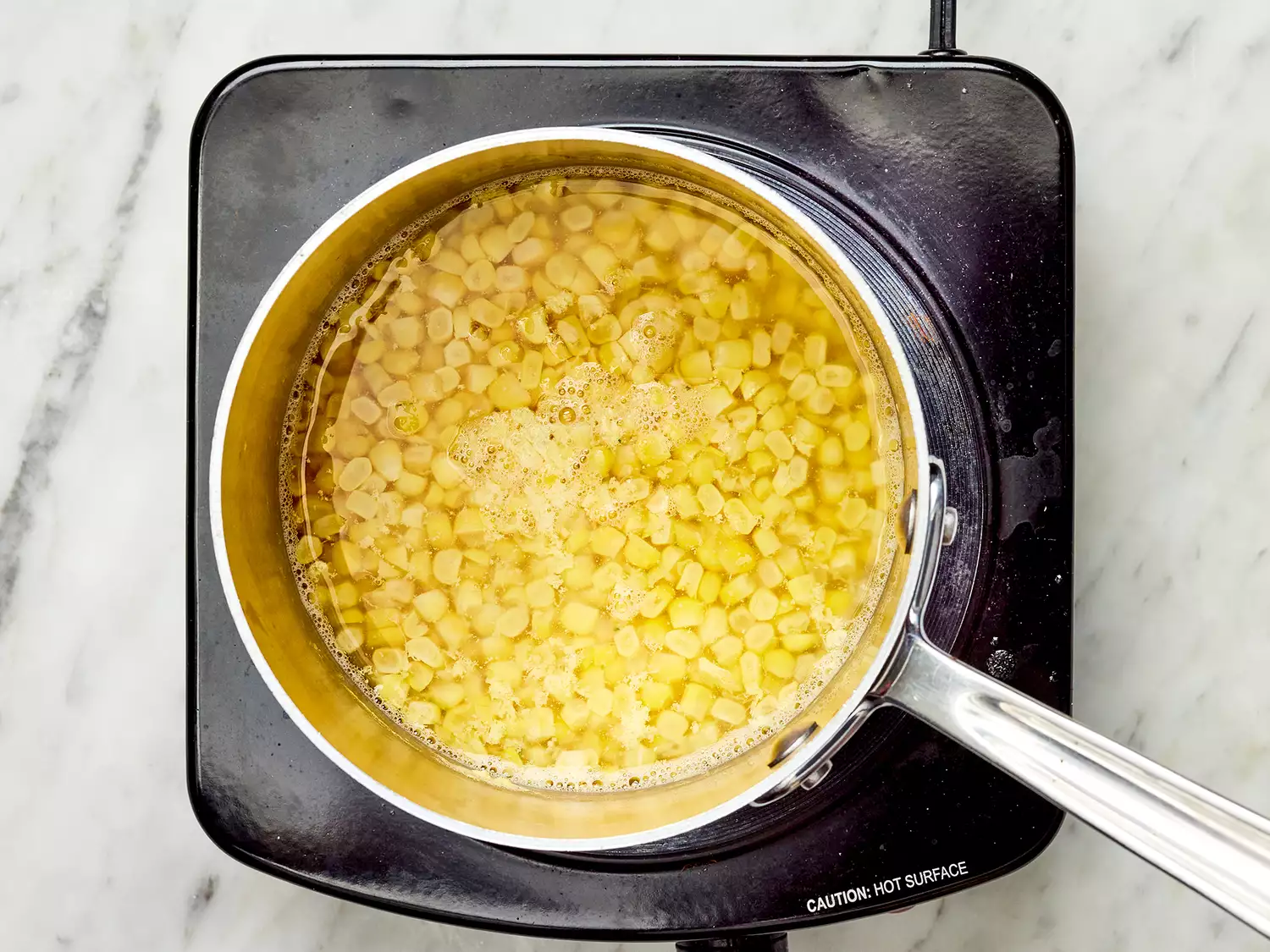 Corn with water in a pot on a burner 