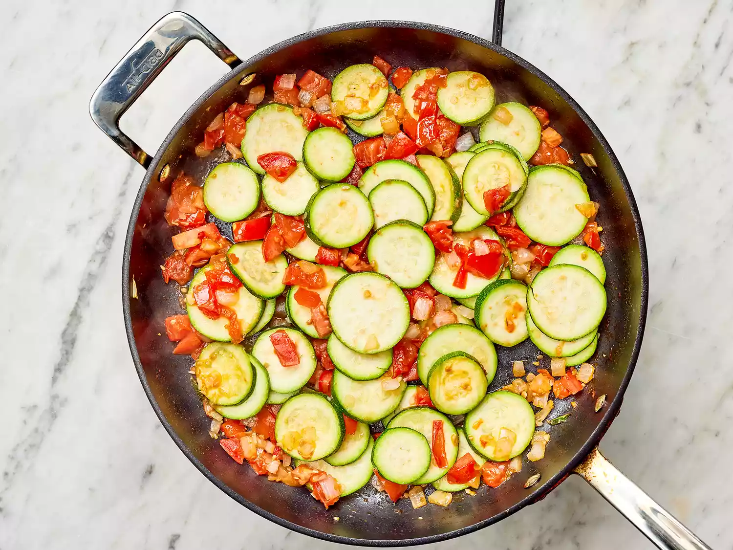 Onions, zucchini and peppers in a pan on a burner 