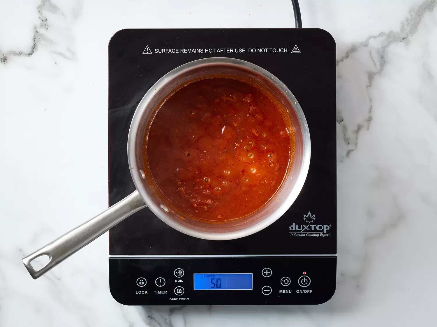 A pot of sauce being heated on an electric cooktop