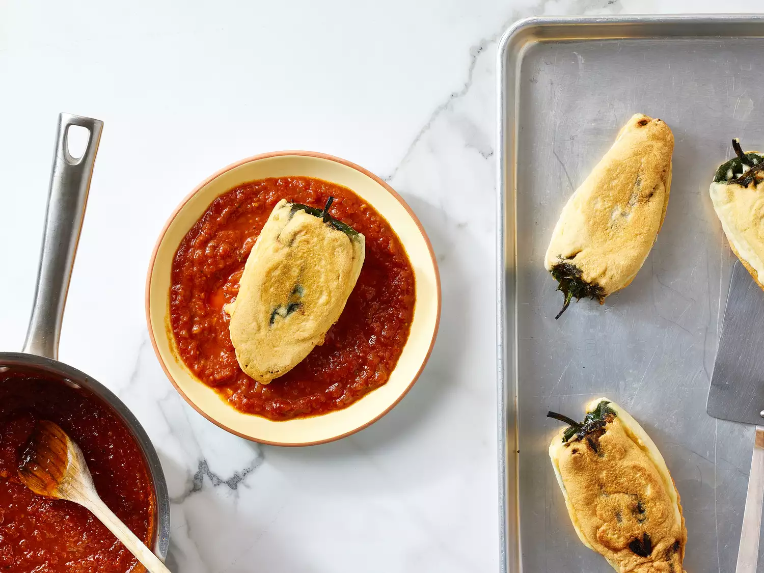 Real Chiles Rellenos with sauce a plate, next to a pot and a baking dish