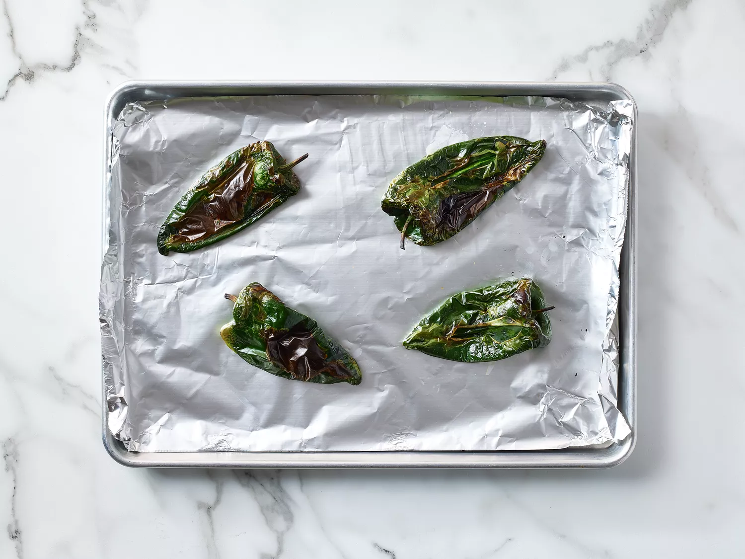Roasted chiles placed on a foil-lined baking sheet