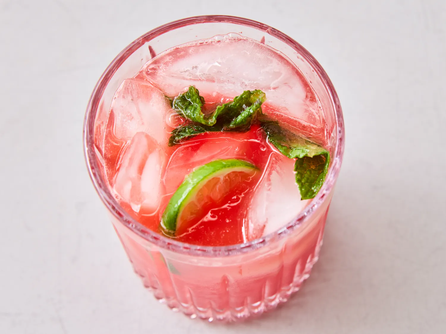 Glass of watermelon agua fresca with ice, lime, and mint leaves